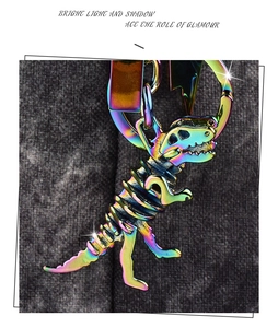 Macro shot of colorful iridescent metal dinosaur skeleton keychain with hook on textured fabric