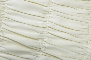 Macro shot showing pleated texture and smooth satin luster of cream chiffon fabric detail