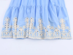 Close-up of sky blue dress hem featuring white floral embroidery and openwork lace detail