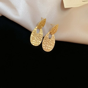 Detailed view of teardrop earrings with vintage gold textured metal finish