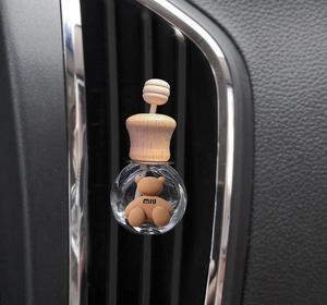 Close-up of a bear-shaped diffuser inside a glass bottle on a car air vent