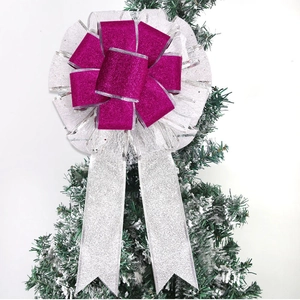 Close-up of a silver glitter bow with magenta ribbon detail on a Christmas tree branch
