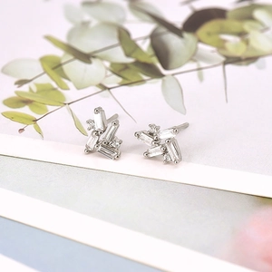 Macro shot of silver geometric earrings with sparkling zircon stones on natural background