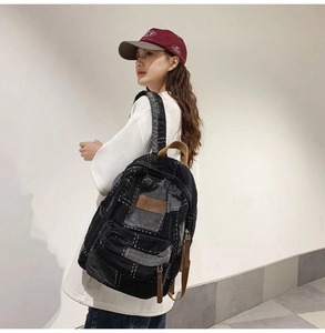 Side view of large denim backpack with white stitching and front pocket on male model