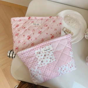 Détail de trousses de maquillage roses matelassées avec motif floral et étiquette