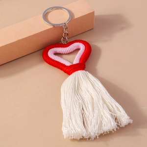 Detailed close-up of handmade knit heart keychain with pink cotton tassel and gold ring