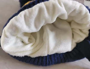 Close-up of the warm white fleece lining and navy knit texture of the children's winter hat