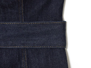 Détail du denim bleu foncé avec coutures contrastées orange et texture sergé