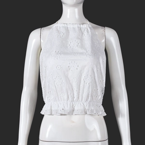 Close-up of white floral embroidery and hollow-out lace detail on cropped halter top