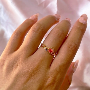 Detail shot of golden ocean animal ring with red and blue zircon on pink silk fabric