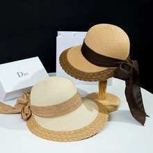 Detailed weave of two wide brim straw hats with brown ribbon on minimalist gift boxes