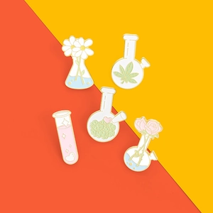 Detailed macro view of enamel flower pins with daisy and rose motifs in lab glassware