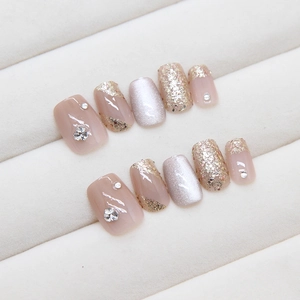 Faux ongles faits main œil de chat rose nude et doré avec des accents de strass