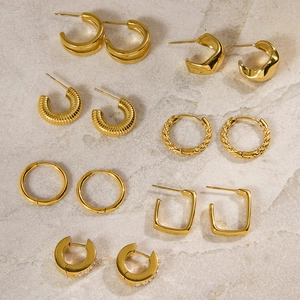 Gros plan de boucles d'oreilles dorées en acier titane avec textures et cristaux