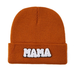 Detail of orange knit beanie featuring MAMA towel embroidered letter patch on cuff