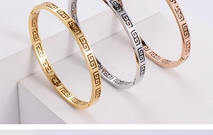 Three stackable geometric hollow bangles in gold, silver and rose gold on white steps