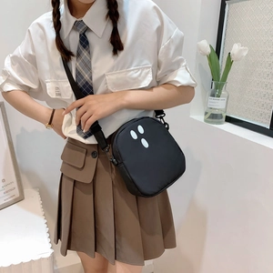 Détail du sac bandoulière noir en nylon avec motifs ovales blancs sur mannequin