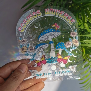 Close-up of holographic suncatcher sticker featuring mushrooms and self-love text