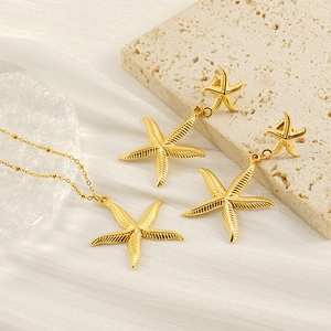 Golden starfish jewelry set with earrings and necklace on a textured stone background