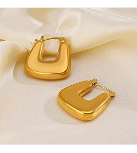 Gros plan de boucles d'oreilles carrées en U plaquées or 18 carats sur tissu en soie beige