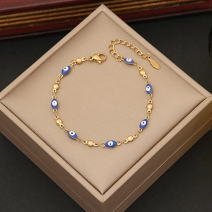 Detail of evil eye bracelet with blue enamel, gold beads, and lobster clasp on jewelry box