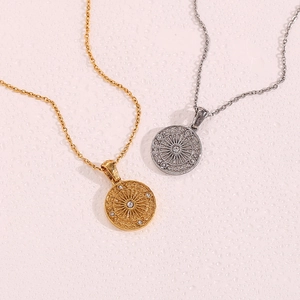 Macro shot of gold and silver compass necklaces with sunburst textures and zircon stones