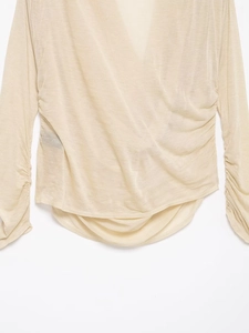 Detailed close-up of beige long sleeve V-neck top with pleated ruching and soft texture