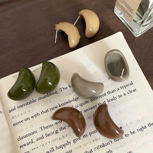 Minimalist geometric resin C-shaped bean stud earrings set in four neutral colors on a book