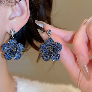Close-up of a deep blue floral zircon earring with intricate layered metal petals