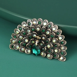 Detailed close-up of a peacock brooch with shimmering green and yellow rhinestones