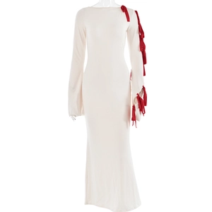 Detail of white slim-fit maxi dress featuring red bow tie accents on long sleeves