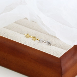 Detailed view of silver and gold snake stud earrings with clear zircons in a jewelry box