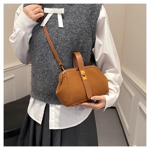 Detailed macro view of brown suede shoulder bag with gold metal buckle and handle