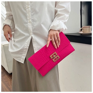 Close-up of vibrant pink crocodile pattern envelope clutch with golden metal lock