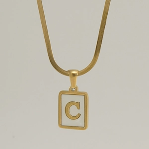 Macro shot of gold square pendant featuring white shell inlay and a raised letter C