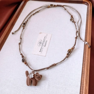 Détail du collier en œil de tigre avec pendentif chat en velours et fleur en argent