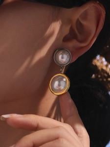 Detailed view of bicolor drop earrings with pearlescent beads on a model's ear