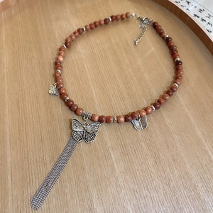 Macro view of ethnic ceramic butterfly necklace with wooden beads and long metal tassels