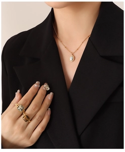 Detail van gouden ketting met marmeren hanger en ringen met natuurstenen bezet