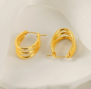 Detailed view of triple-layered golden stainless steel hoop earrings on a white surface