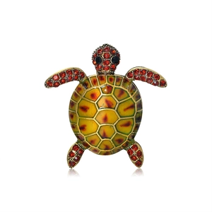 Macro shot of sea turtle brooch featuring yellow enamel shell and red crystal detailing