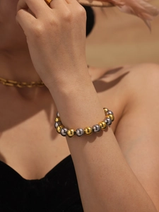 Detailed close-up of mixed gold and silver polished hollow steel bead bracelet on wrist
