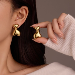 Élégantes boucles d'oreilles en acier inoxydable à double cœur doré portées par un mannequin