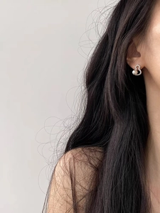 Macro shot of silver pearl gourd earrings with shimmering zircons on model ear