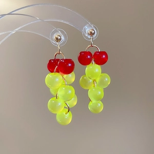 Detail shot of red and green resin grape cluster tassel earrings hanging on a display