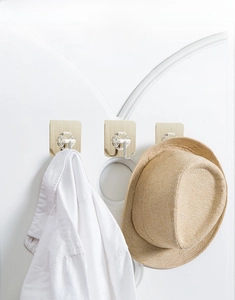 Three adhesive wall hooks with flower-shaped bases and metal hooks on a white door