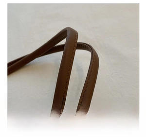 Macro detail of the comfortable brown leather shoulder strap with double stitching