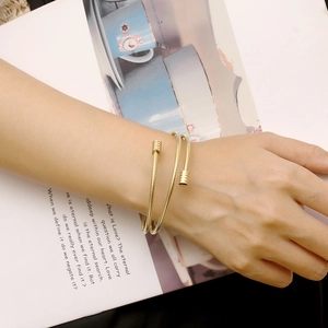 Detail of 18k gold plated multi-layer cable spring cuff bracelet on a model's wrist