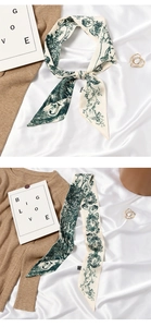 Detail of a beige silk scarf with green floral print used as a necktie and hair ribbon