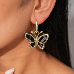 Close-up of butterfly hoop earrings featuring purple and black acetate inlay in gold frame